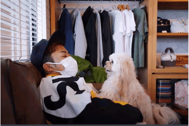 a man wearing a mask is laying on a couch with a dog and the number 5 on his shirt