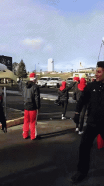 a group of people wearing santa hats are walking down a street in front of a sign that says ' a ' on it