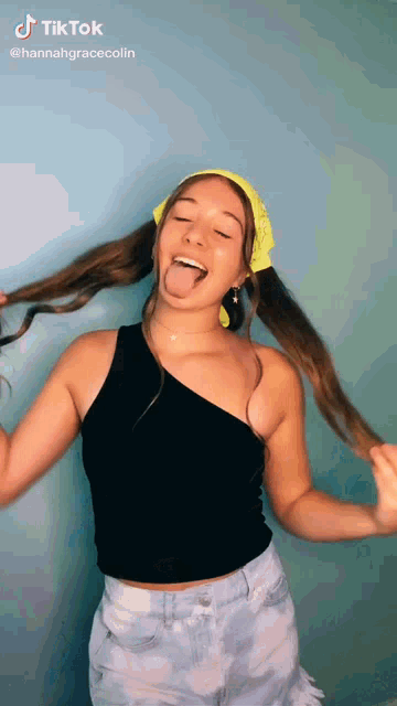 a woman is sticking her tongue out while wearing a bandana and a black top