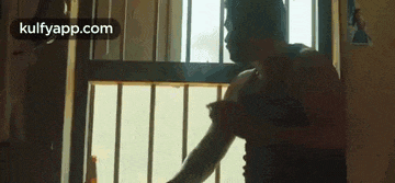 a man is standing in front of a window holding his arm .