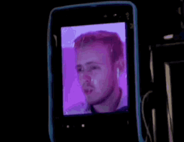 a man 's face is displayed on a cell phone screen