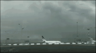 an airplane is taking off from an airport runway with a storm in the background