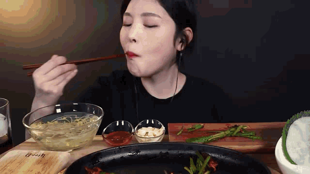 a woman is eating food with chopsticks from a bowl on a table