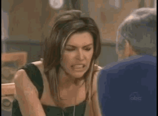 a woman is holding her head in pain while talking to another woman .