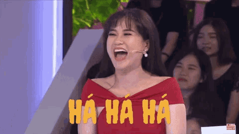 a woman in a red dress is laughing in front of a crowd and the words ha ha ha are above her
