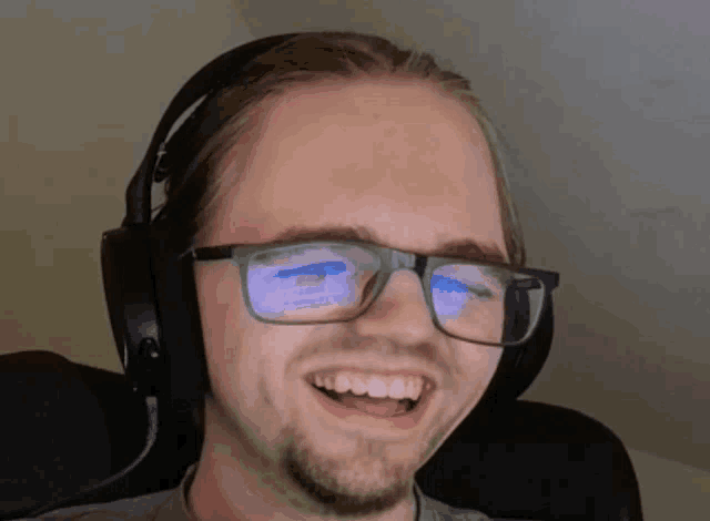a man wearing headphones and glasses is smiling