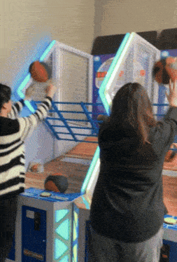 two people are playing a game of basketball and one of them is wearing a black jacket