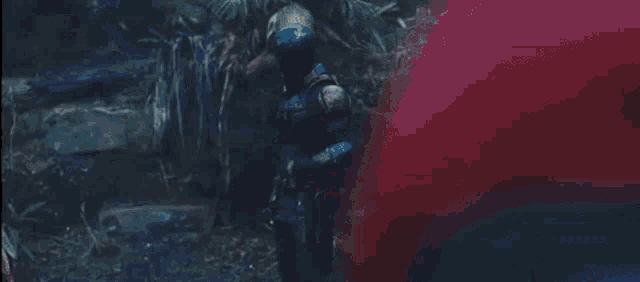a man in a superhero costume is standing in the woods .