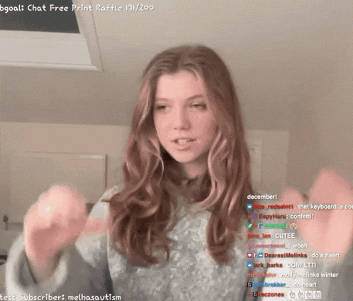 a girl in a grey sweater is talking on a twitch stream