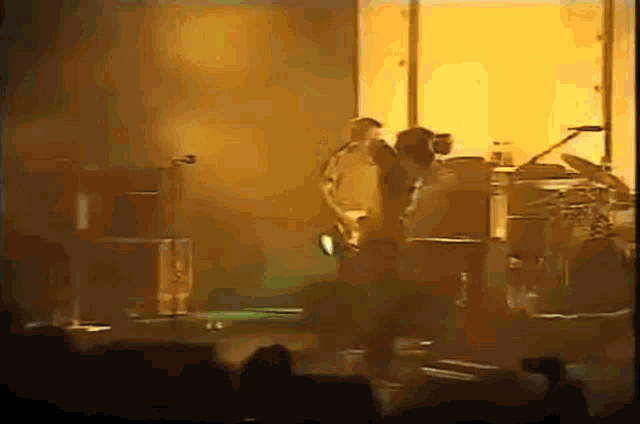 a man is playing a guitar on a stage in front of a crowd of people .