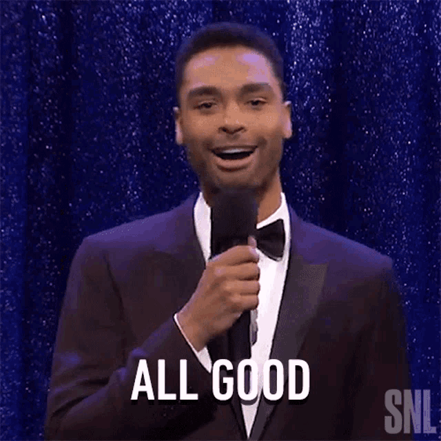 a man in a tuxedo is holding a microphone and smiling .