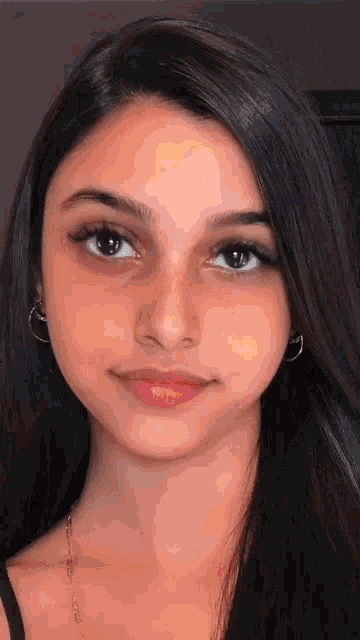 a close up of a woman 's face with long hair and earrings