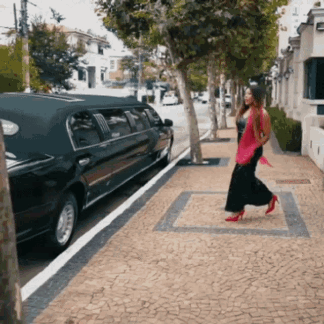 a woman is walking down a sidewalk next to a limousine