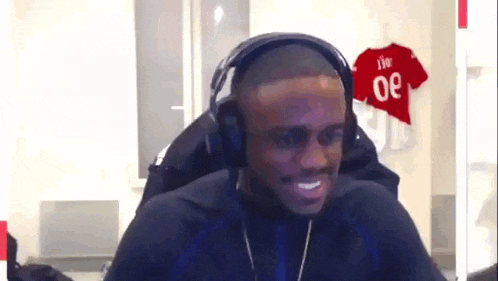 a man wearing headphones is smiling in front of a red jersey with the number 30 on it