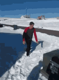 a young boy in a red shirt is walking through the snow