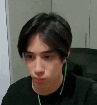 a young man wearing headphones is making a funny face while sitting at a desk .