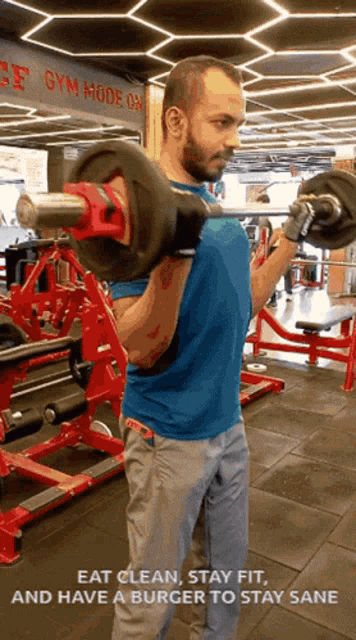 a man is lifting a barbell in a gym with the words eat clean stay fit and have a burger to stay sane below him