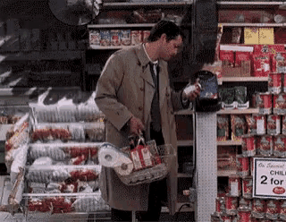 a man in a trench coat is shopping in a grocery store with a sign that says 2 for