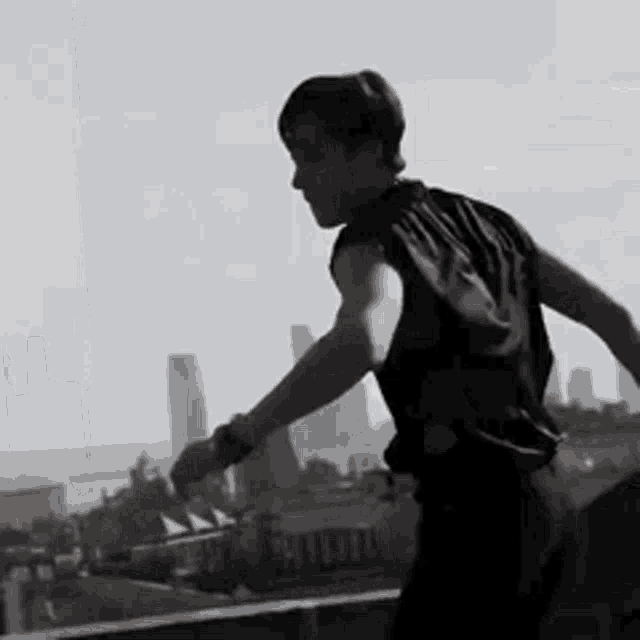 a man in a black shirt is standing on a balcony overlooking the city .