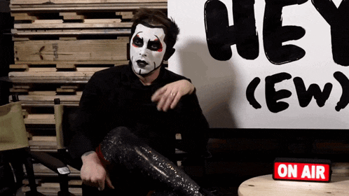 a man is sitting in front of a sign that says hey crew