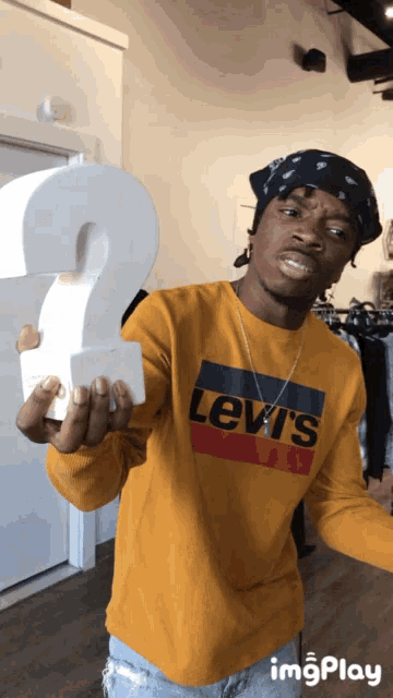 a man wearing a yellow levi 's shirt holds a question mark