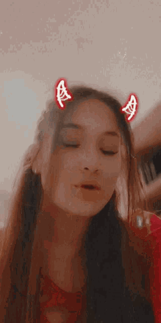 a girl with devil horns on her head making a face