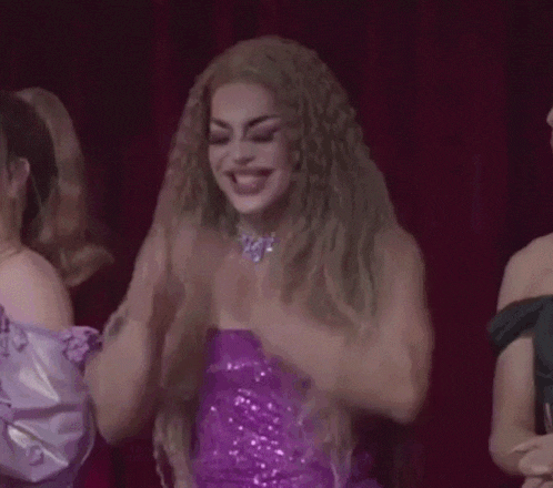 a woman in a purple dress is covering her face with her hands while standing next to two other women .