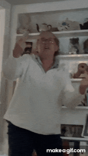a woman in a white sweater is dancing in front of a shelf full of stuffed animals ..