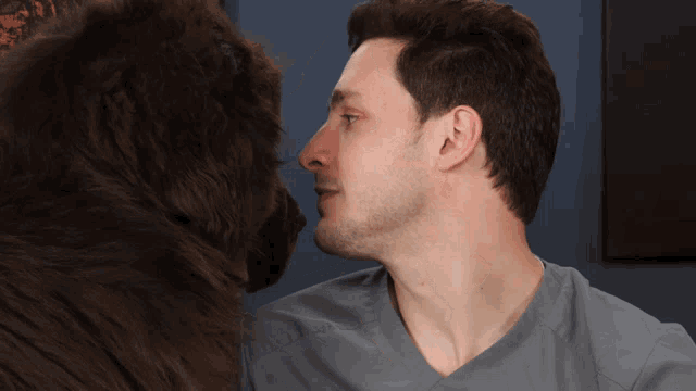 a man in a scrub top is looking at a brown dog