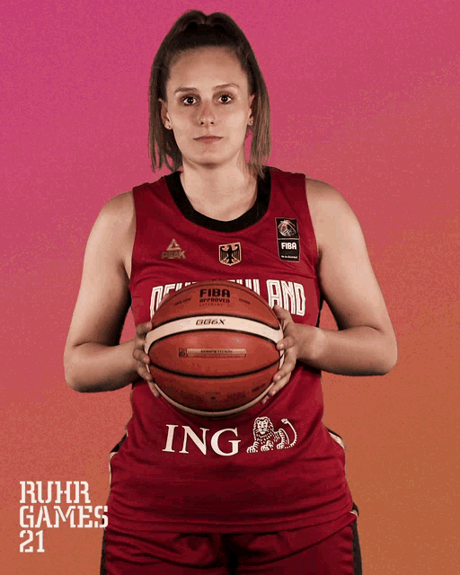 a female basketball player holds a basketball with the word ing on it