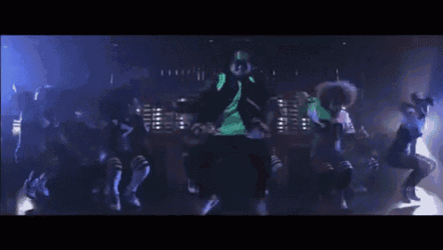 a man in a green shirt is dancing in a dark room