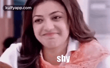 a woman is smiling and making a funny face with the word shy written on her face .