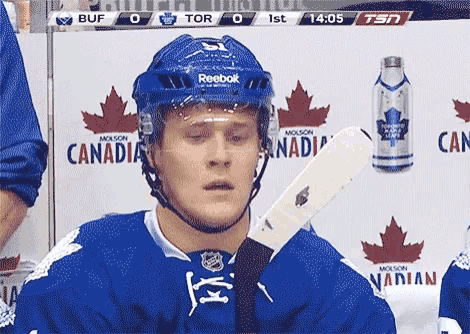 a hockey player wearing a reebok helmet holds his stick