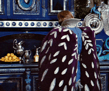 a woman in a purple cape stands in front of a blue dresser