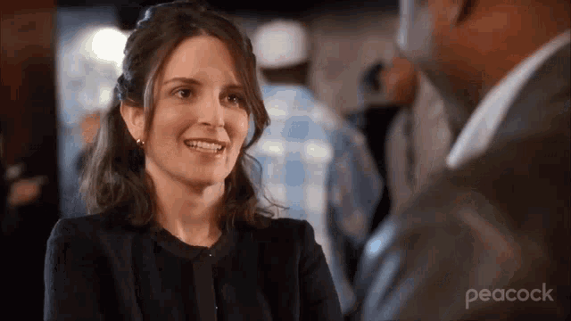 a woman is smiling while talking to a man in a peacock ad .