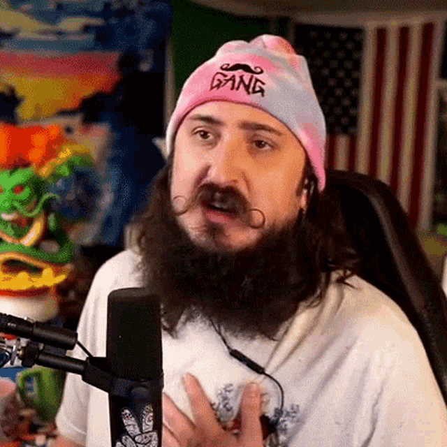 a man with a beard wearing a pink hat that says gang on it