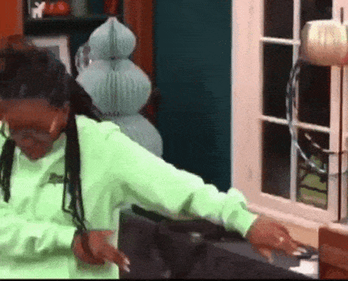 a woman in a neon green sweatshirt is sitting in front of a window .