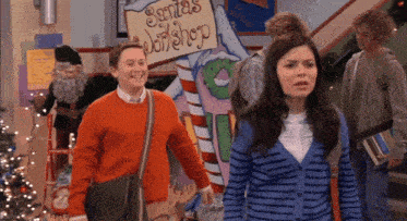 a boy and a girl are walking in front of a sign that says santas workshop