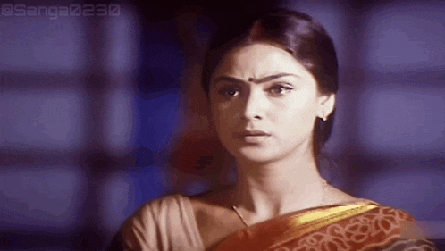 a woman in a sari is looking at the camera with a surprised expression on her face .