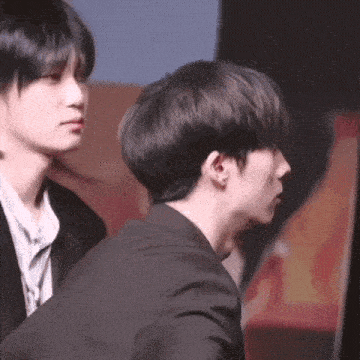 two young men are standing next to each other and one of them is wearing a black suit .