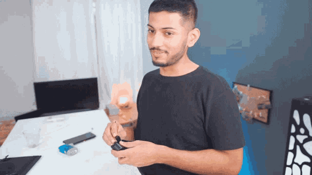 a man with a beard wearing a black shirt is holding something in his hands