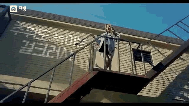 a woman stands on a set of stairs in front of a brick building with chinese writing on it