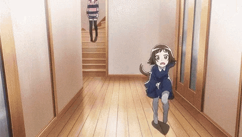 a little girl in a blue dress is running down a hallway next to a woman in a pink sweater .