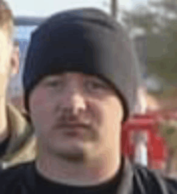 a man wearing a black hat and a black shirt is standing in front of a group of people .