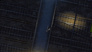 an aerial view of a train station at night with a person walking down the street