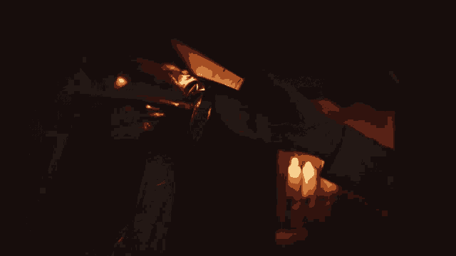 a person is opening a bottle of wine in a dark room with candles in the background