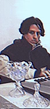 a blurry picture of a man sitting at a table with a reflection of him in a mirror