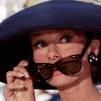 a woman wearing a hat and sunglasses looks at something