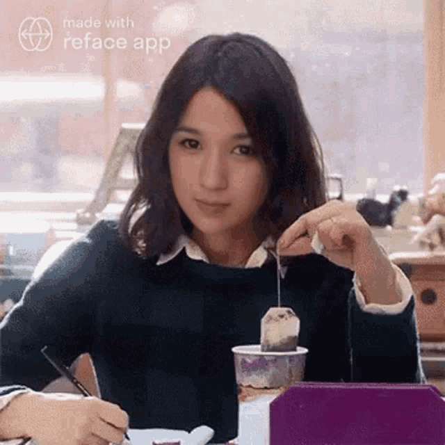 a woman is sitting at a table holding a tea bag in her hand .