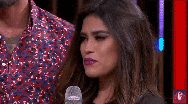 a woman is standing in front of a microphone with a man standing behind her .